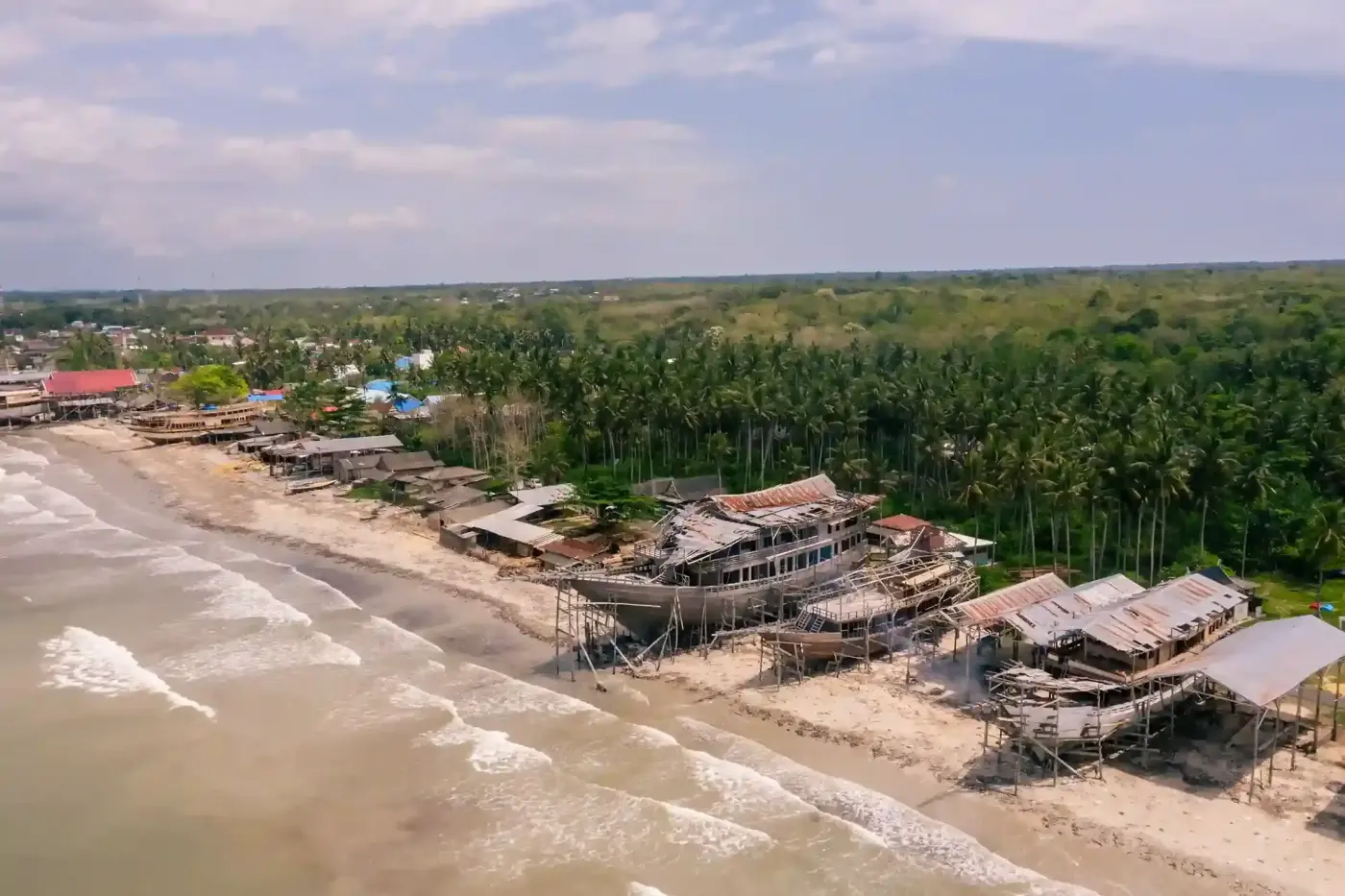 Phinisi hulls under construction on a beach shipyard