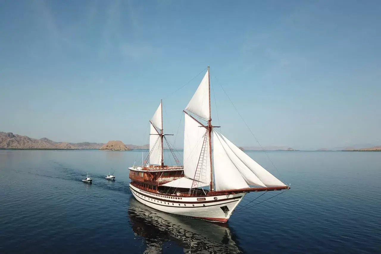White phinisi with sails up on a calm sea