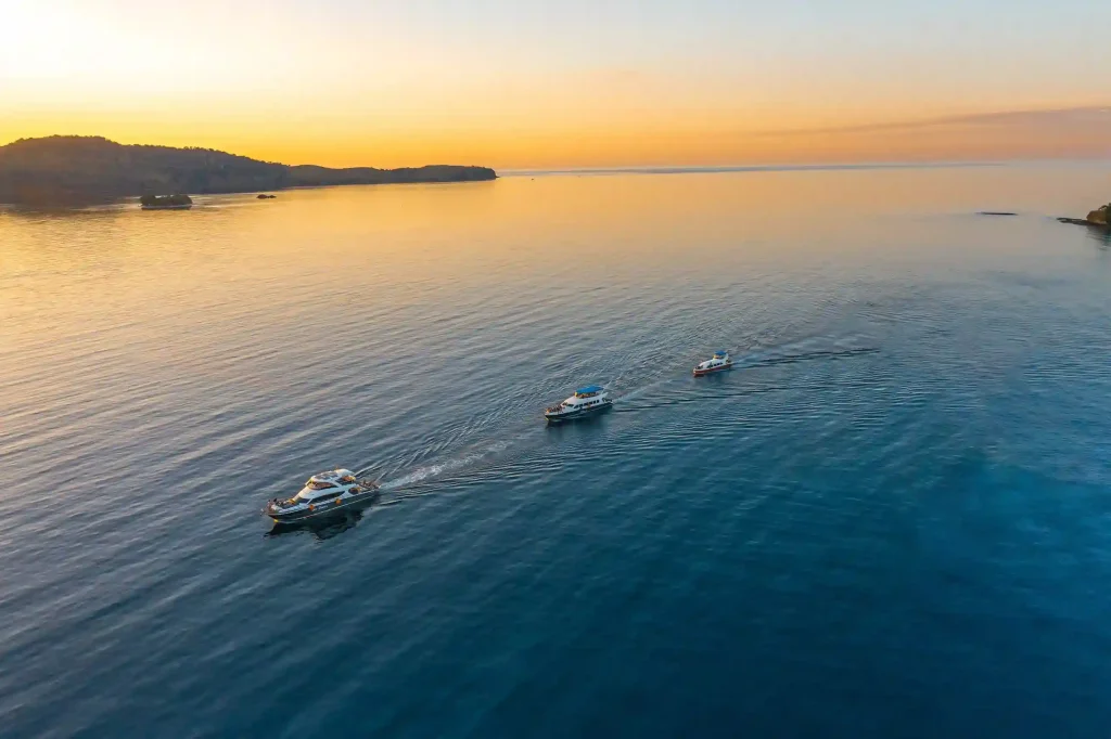 Speedboats crossing a calm sea at sunset off the Komodo islands