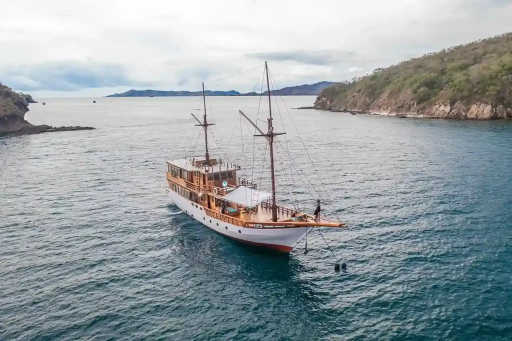 Aerial view of a wooden phinisi at anchor in a sheltered bay