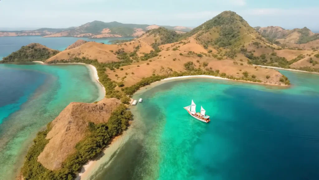 Aerial view of a private phinisi anchored off a Komodo island beach